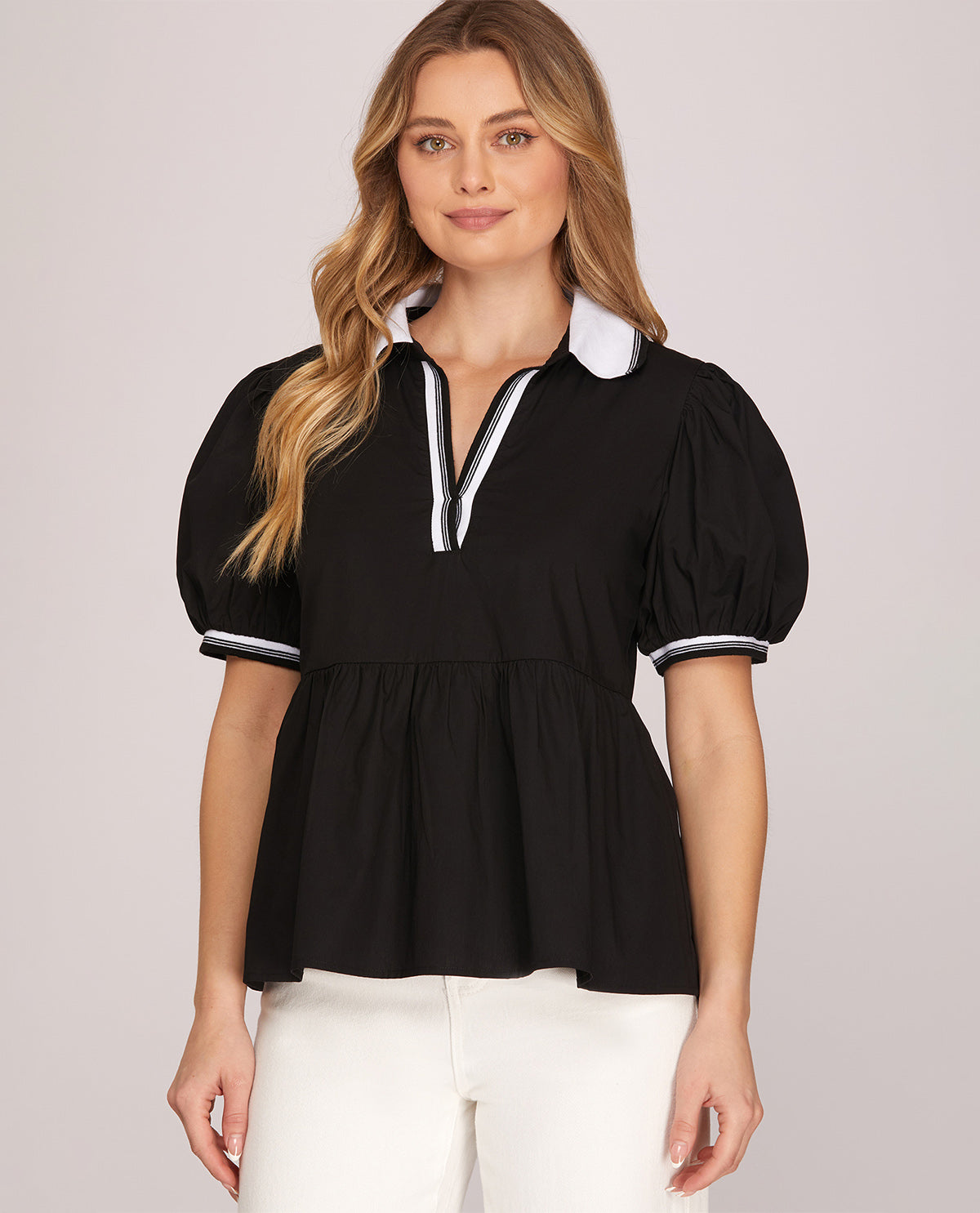 Woman wearing a black blouse with white trim on a light gray background