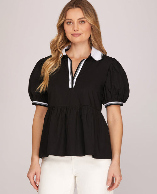 Woman wearing a black blouse with white trim on a light gray background