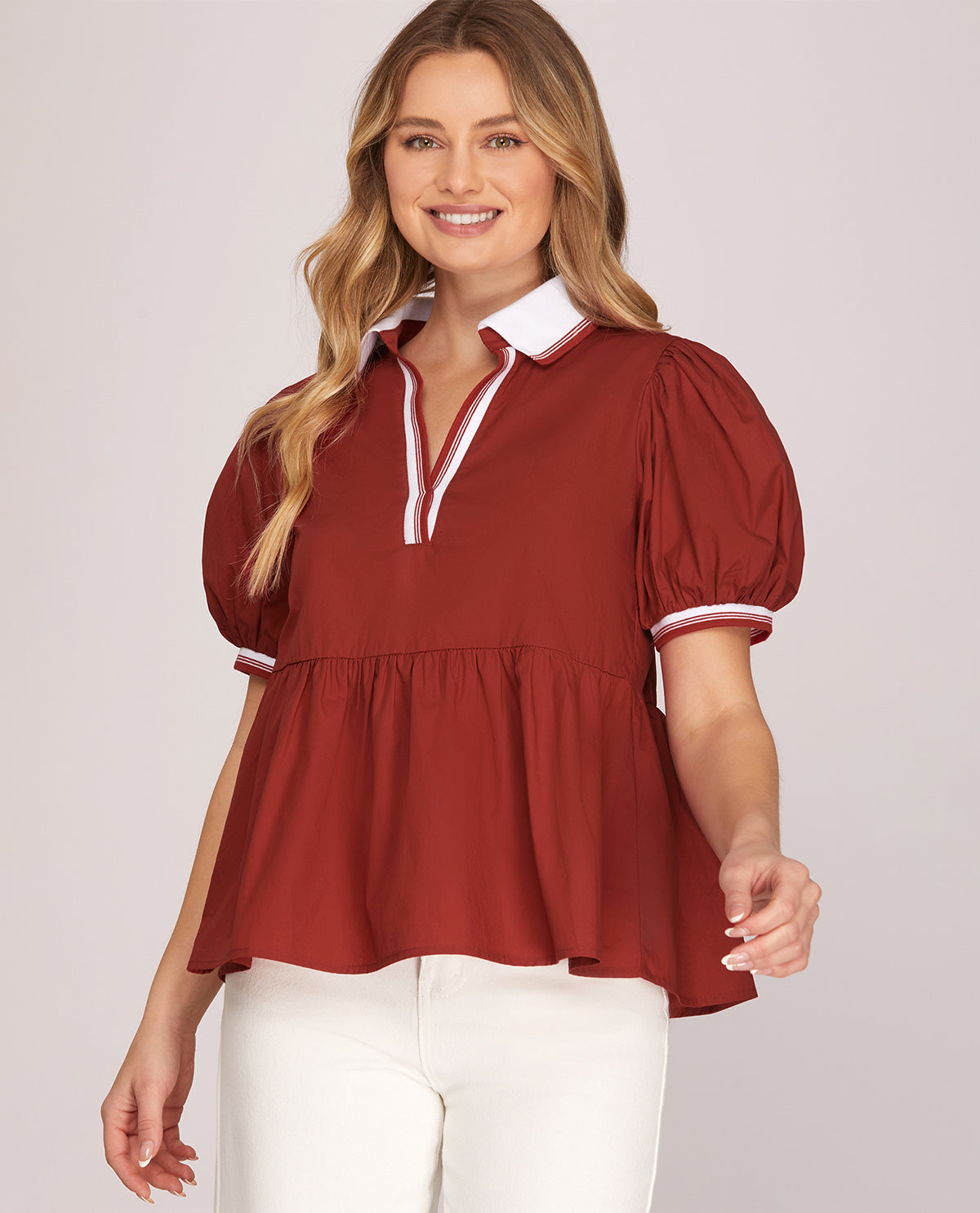 Woman wearing a red blouse with white trim on a plain background