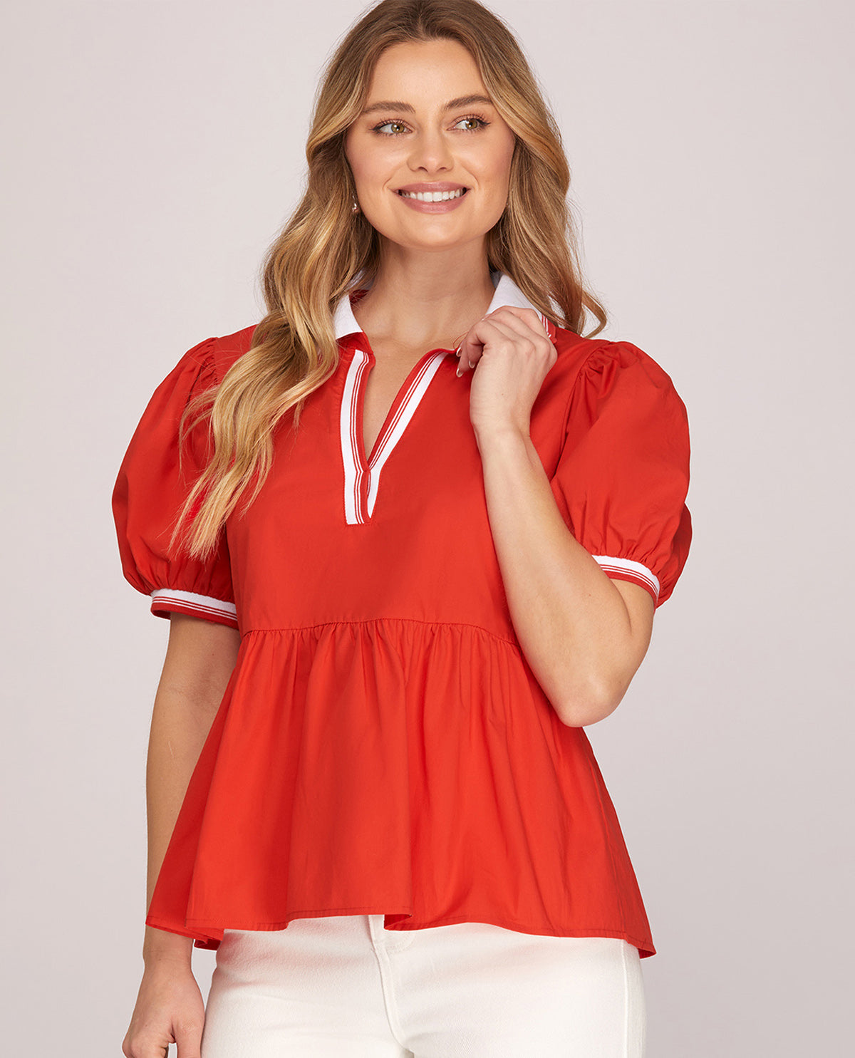 Woman wearing a red blouse with white trim on a light gray background