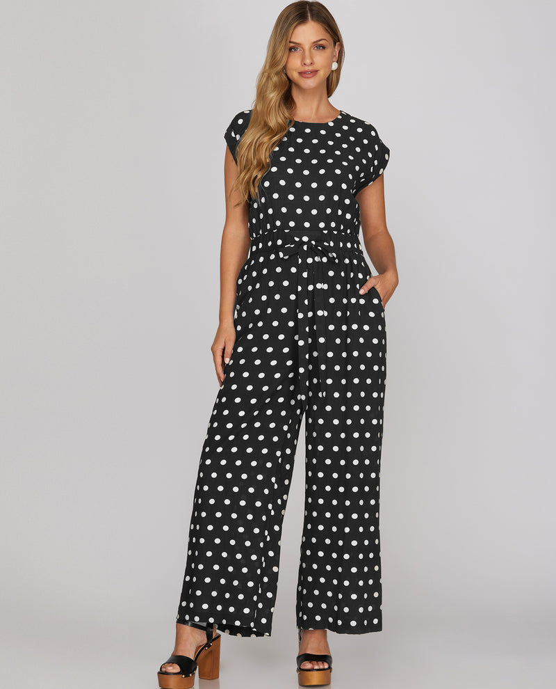 Woman wearing a black polka dot jumpsuit on a gray background