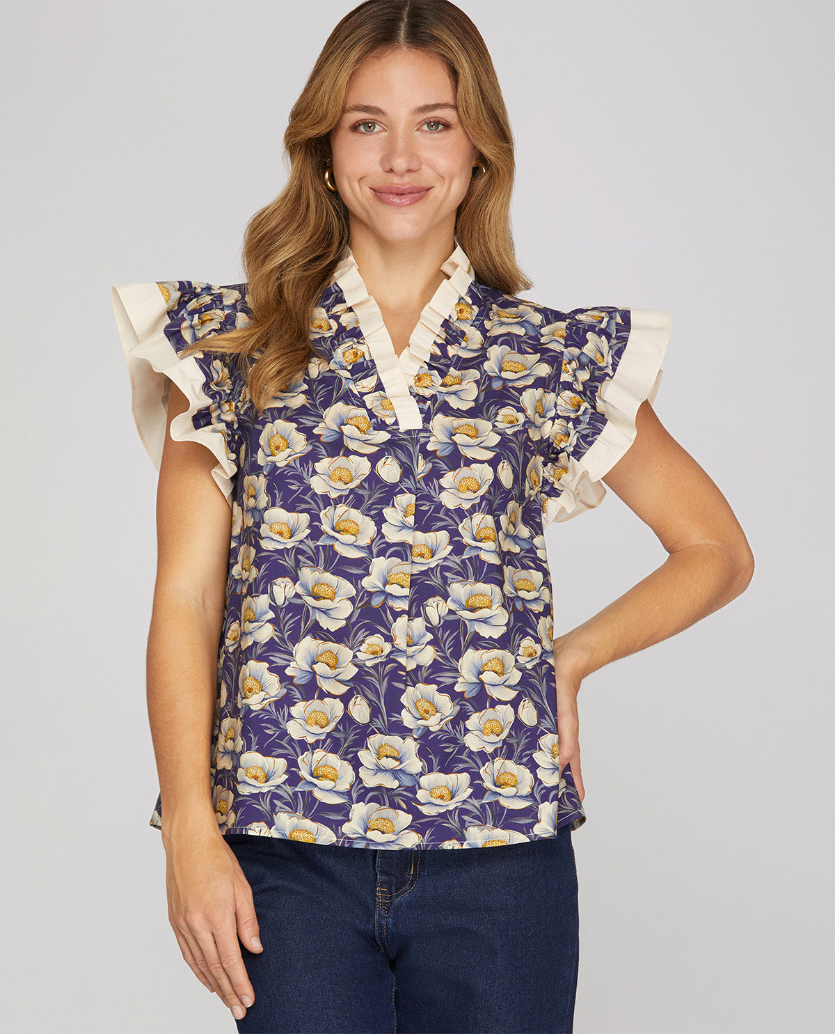 Woman wearing a floral blouse with ruffled sleeves on a plain background