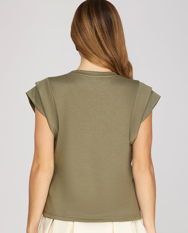 Woman wearing a green sleeveless top against a plain background