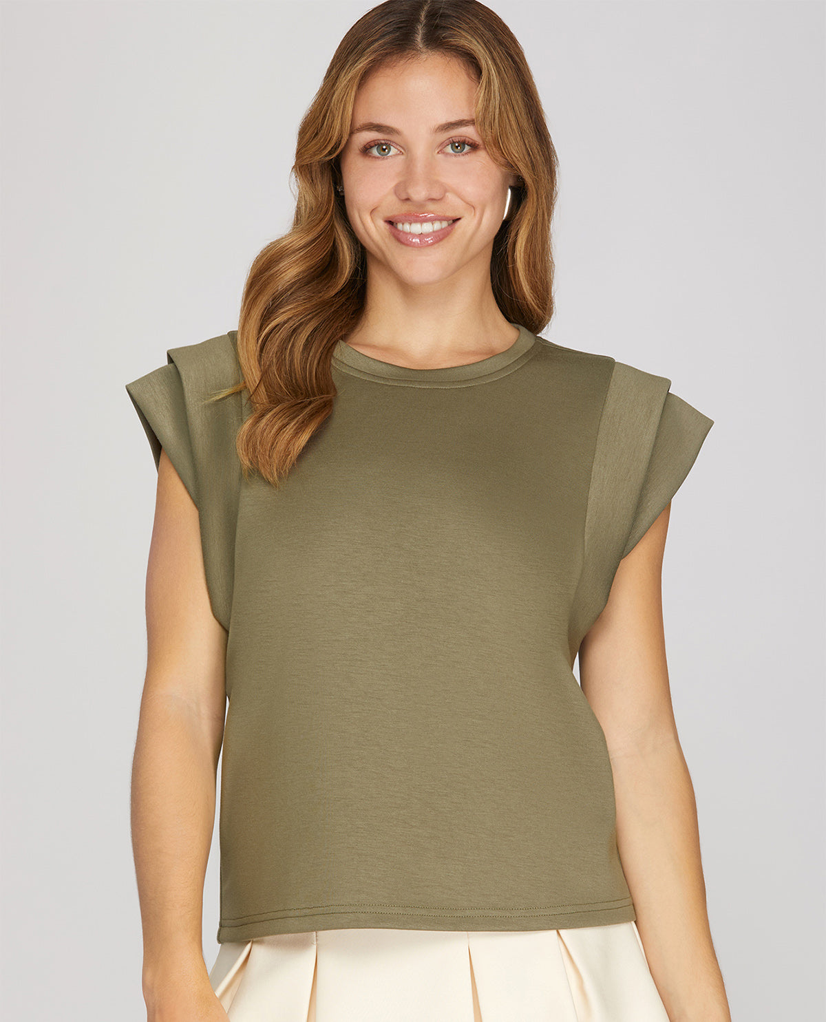 Woman wearing an olive green sleeveless top against a plain background