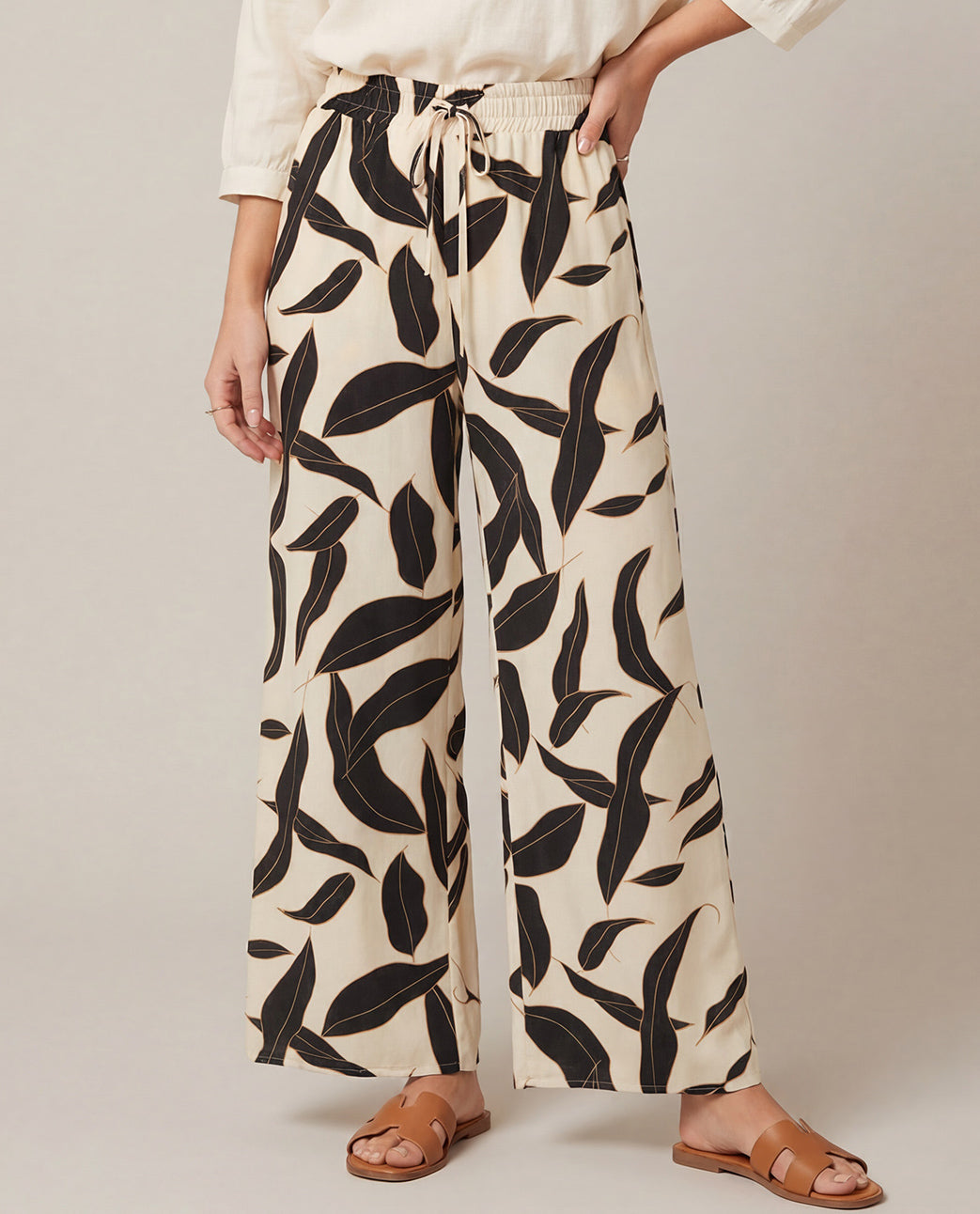 Missy size model wearing wide leg black/cream pants with a leaf pattern