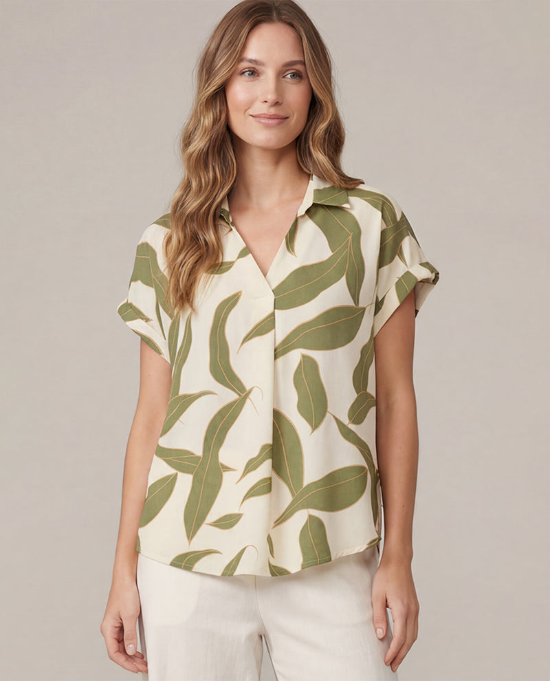 Woman wearing a leaf-patterned shirt against a plain background