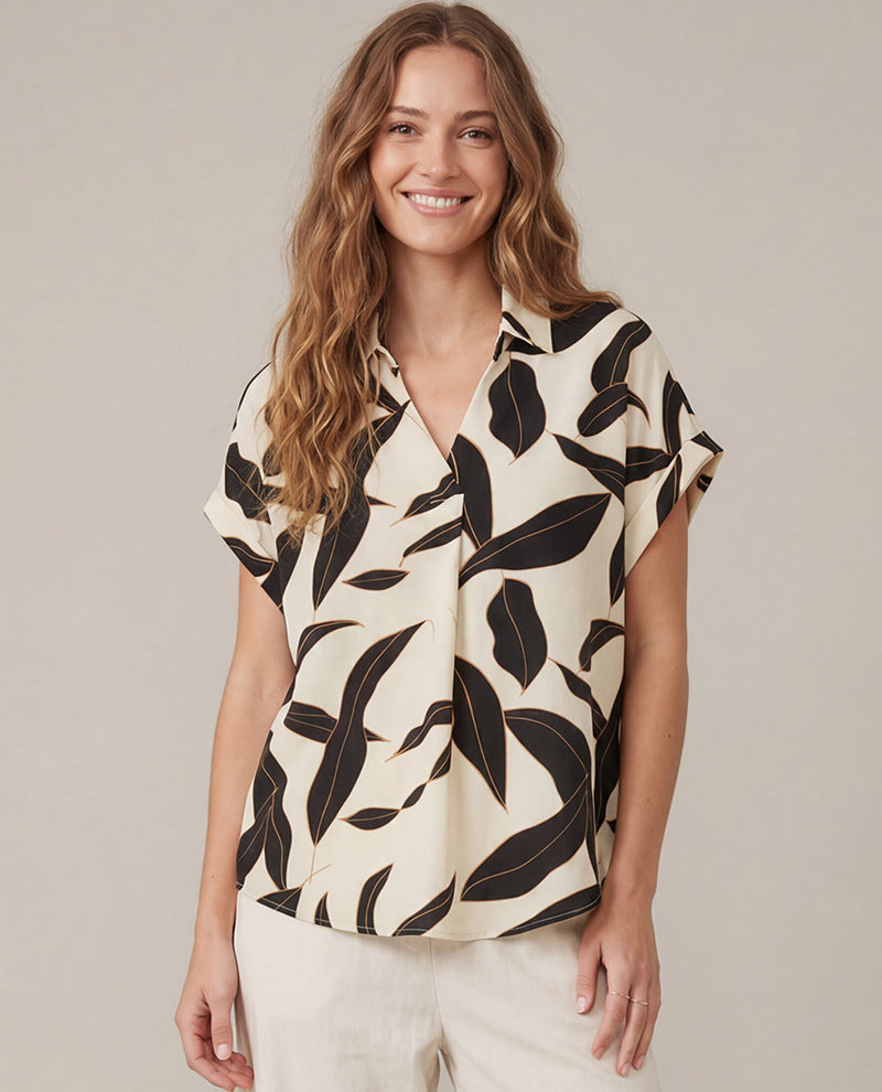 Woman wearing a short sleeve leaf patterned black/cream blouse