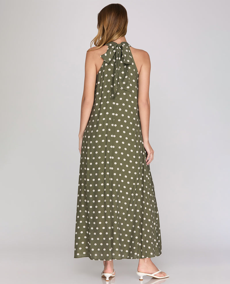 Woman wearing a green polka dot halter neck dress on a plain background