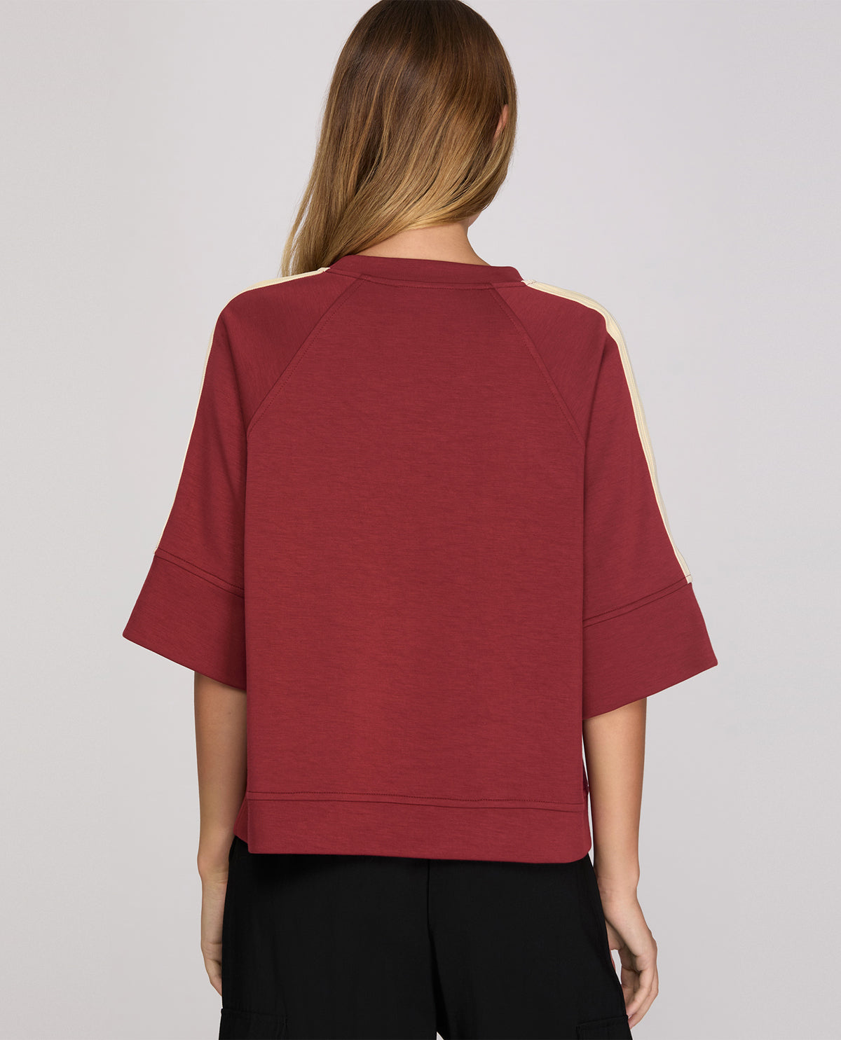 Back view of a person wearing a maroon sweater on a plain background