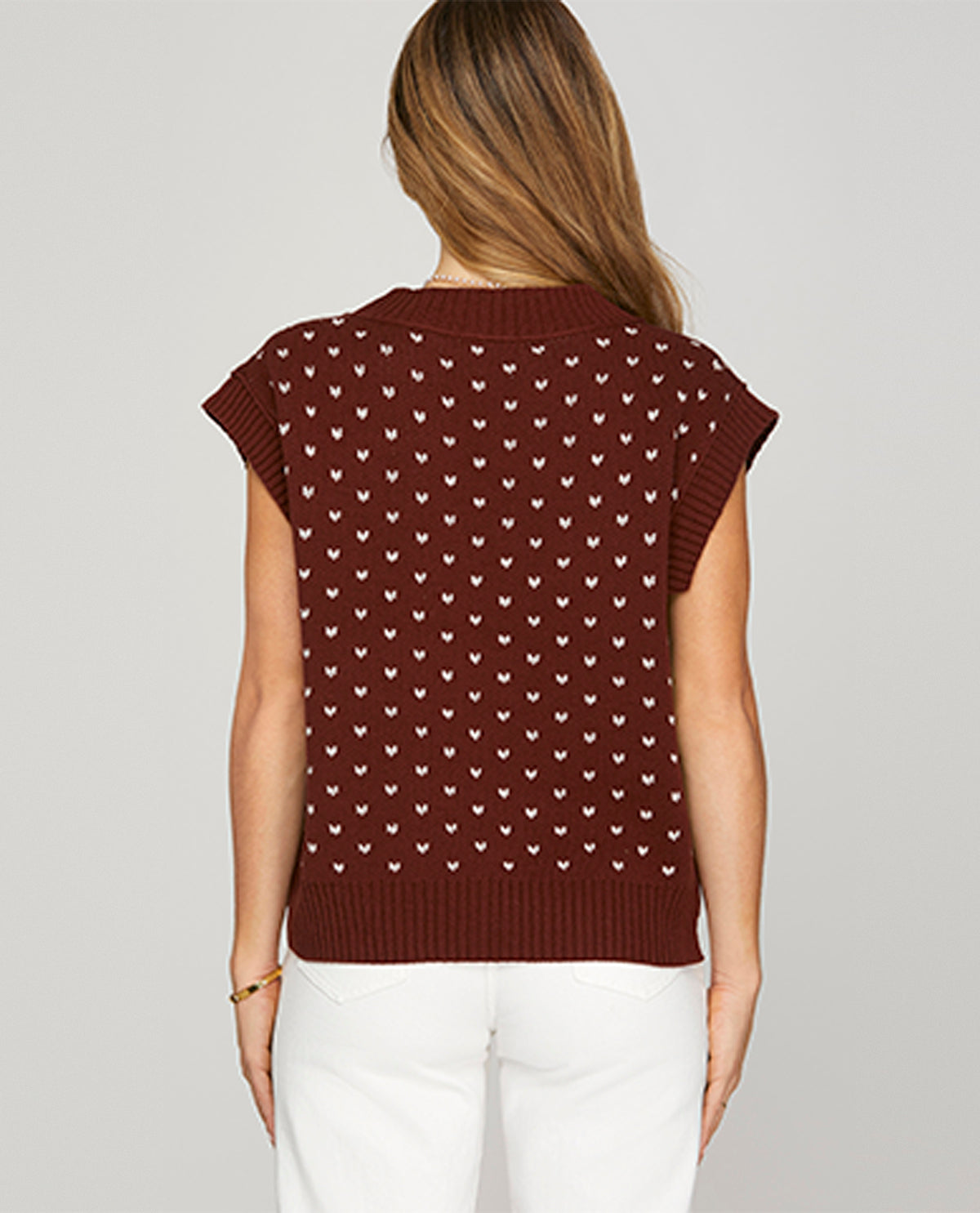Brown patterned sleeveless sweater worn by a person on a plain background