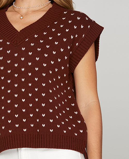 Brown sleeveless sweater vest with white pattern on a neutral background