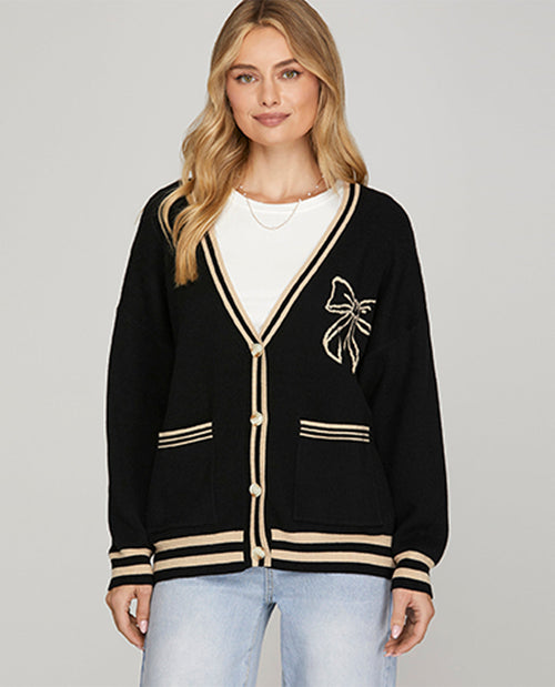 Woman wearing a black cardigan with a bow design on a gray background