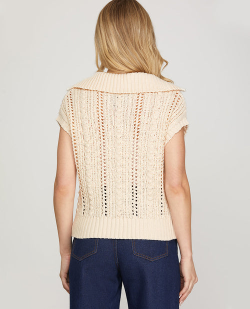 Woman wearing a beige knitted vest on a plain background