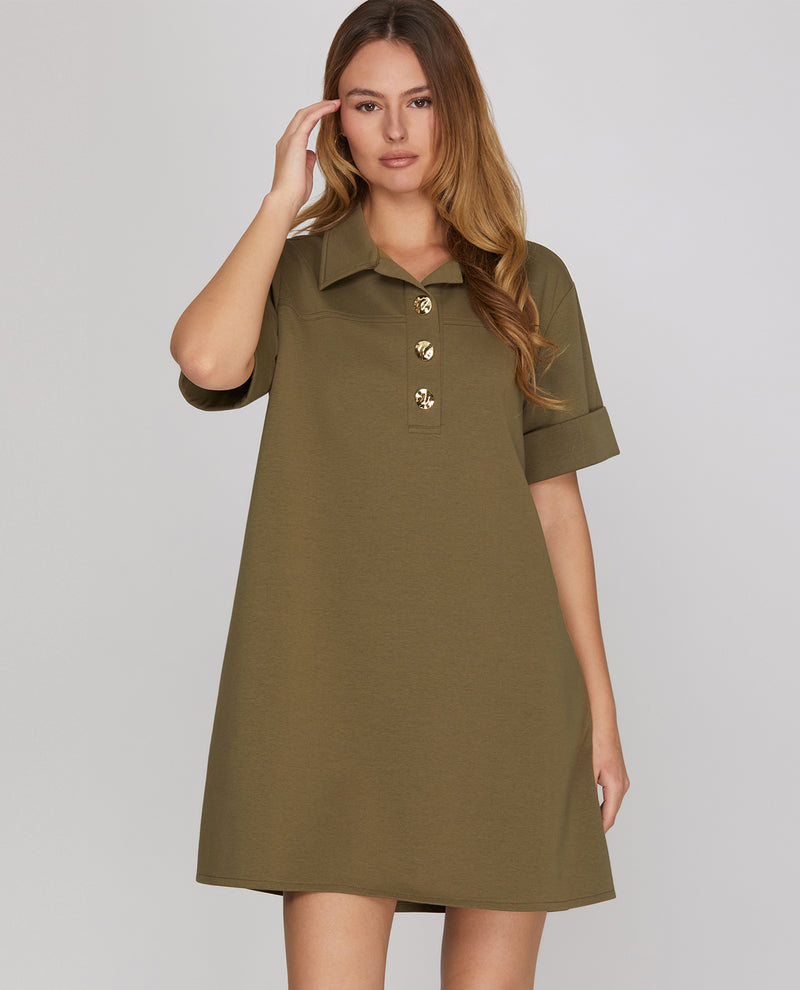 Woman wearing a green dress with buttons on a gray background