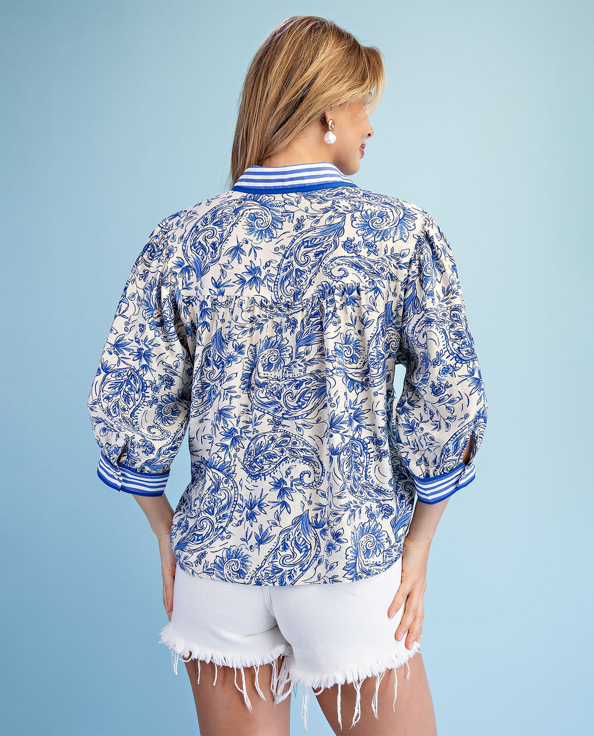 Woman wearing a blue and white patterned shirt with a plain background