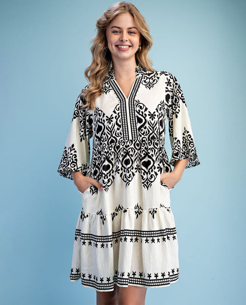 Woman wearing a black and white patterned dress against a light blue background