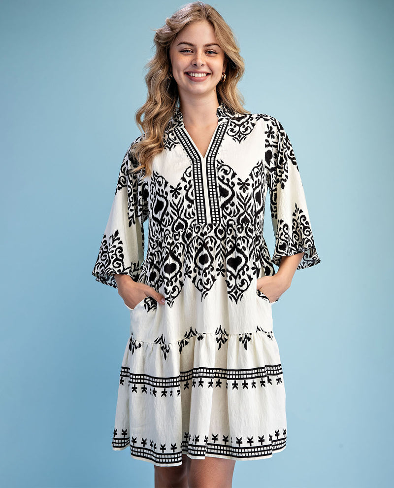 Woman wearing a black and white patterned dress against a light blue background