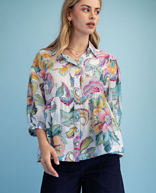 Woman wearing a colorful floral blouse against a blue background