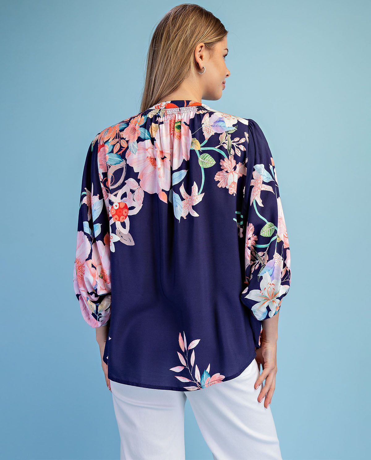 Woman wearing a navy floral blouse against a blue background