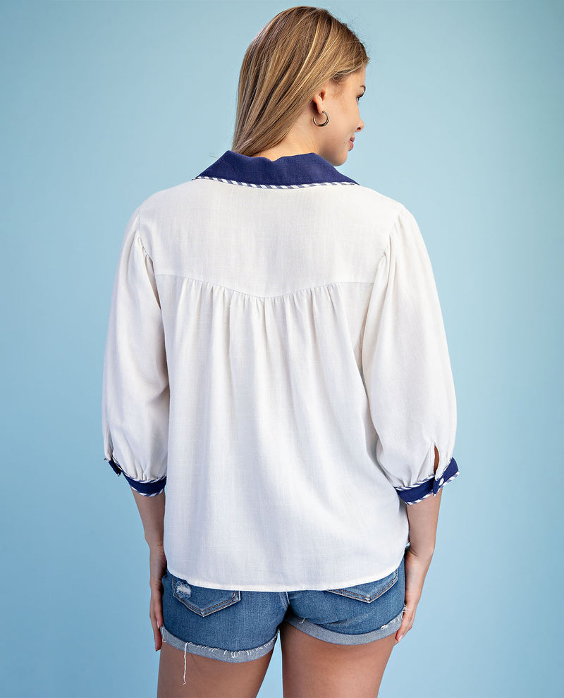 Woman wearing a white blouse with blue accents on a light blue background