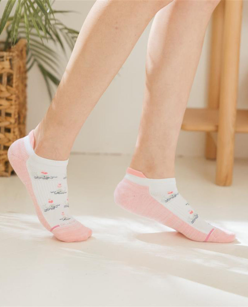 Person wearing white socks with pink toes and heels on a light-colored floor.