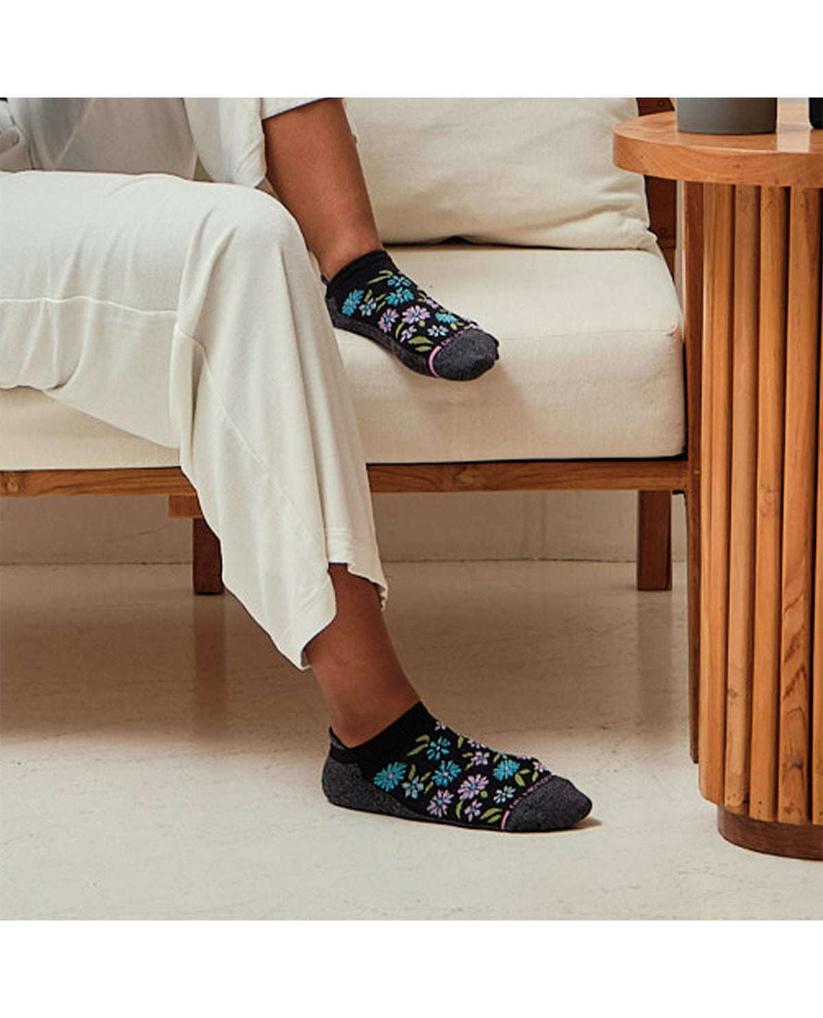 Person sitting on a chair wearing floral-patterned socks in a home setting.