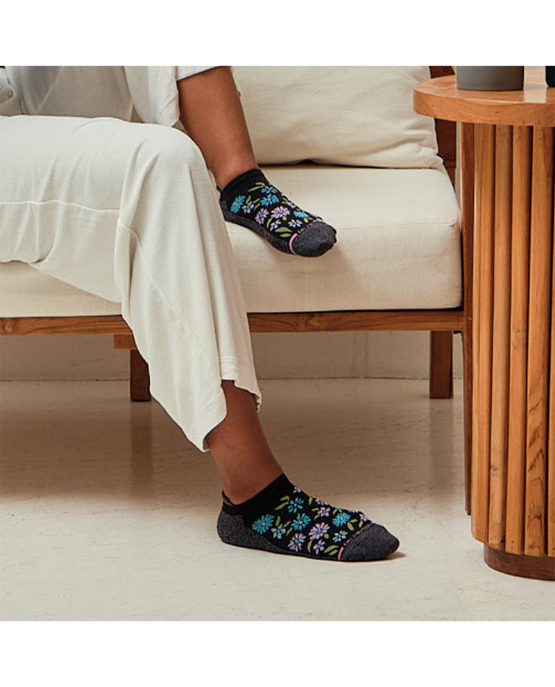 Person sitting on a chair wearing floral-patterned socks in a home setting.