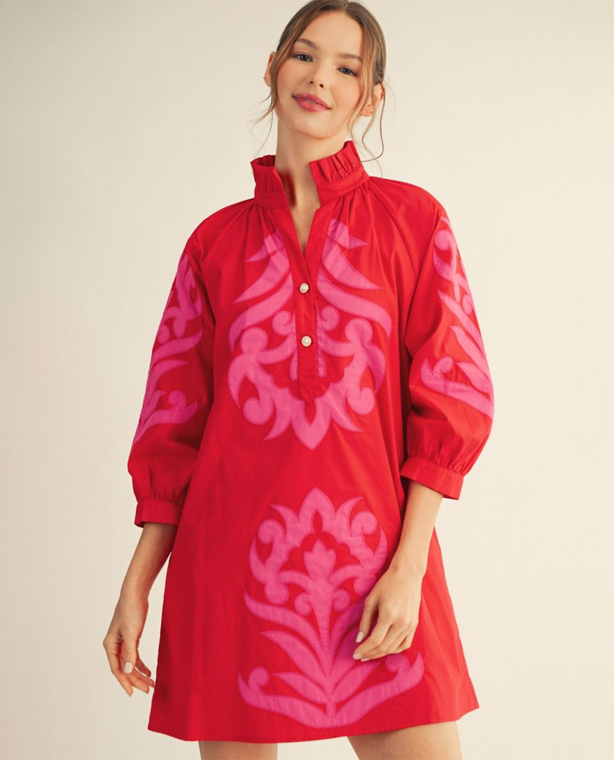 Woman wearing a red dress with pink floral patterns on a beige background